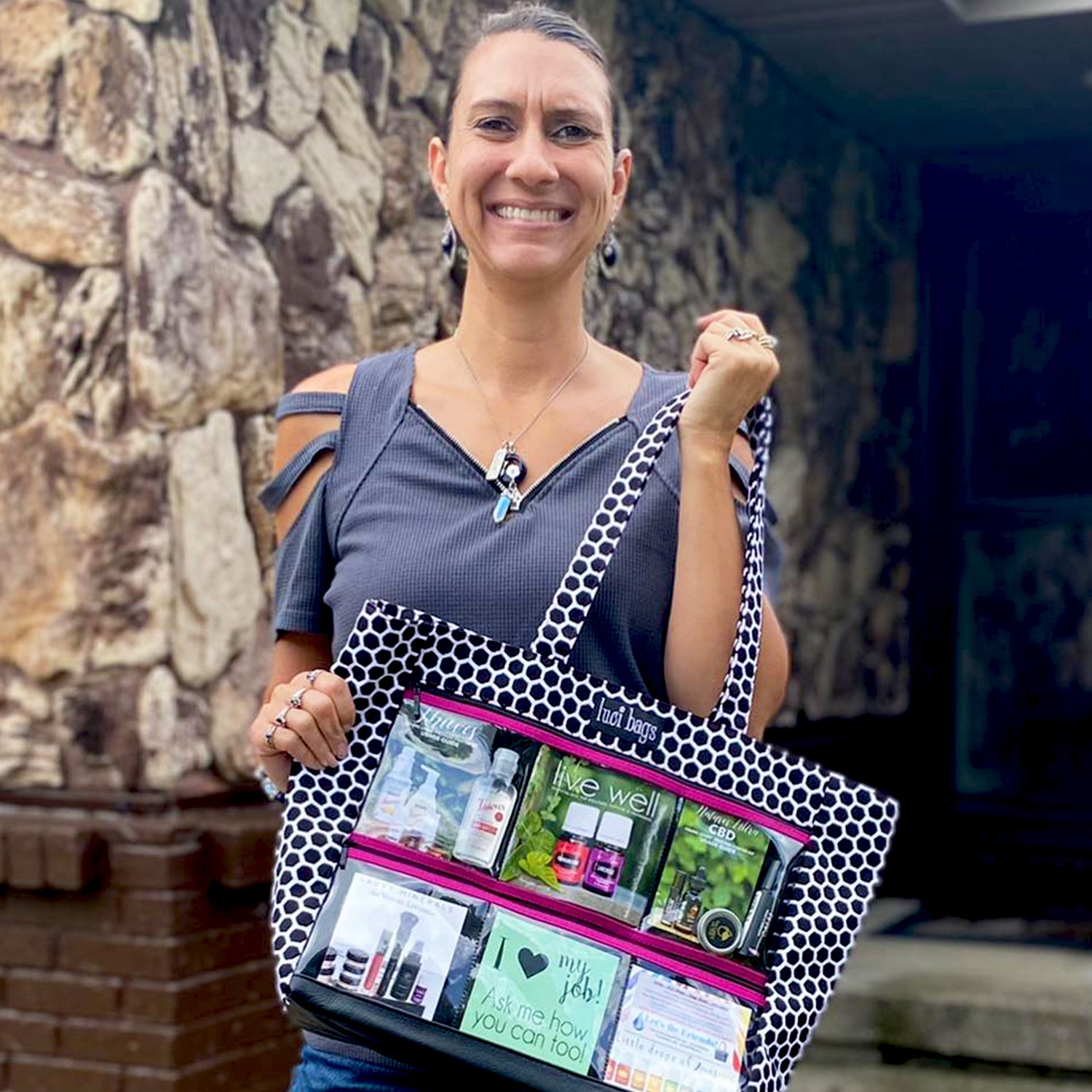 Woman holding a black and white bag with pink trim. Pockets are filled with images marketing her oil business.