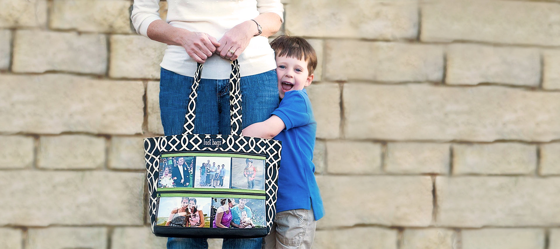Grandma holding a black lattice photo handbag while little boy hugs her leg.