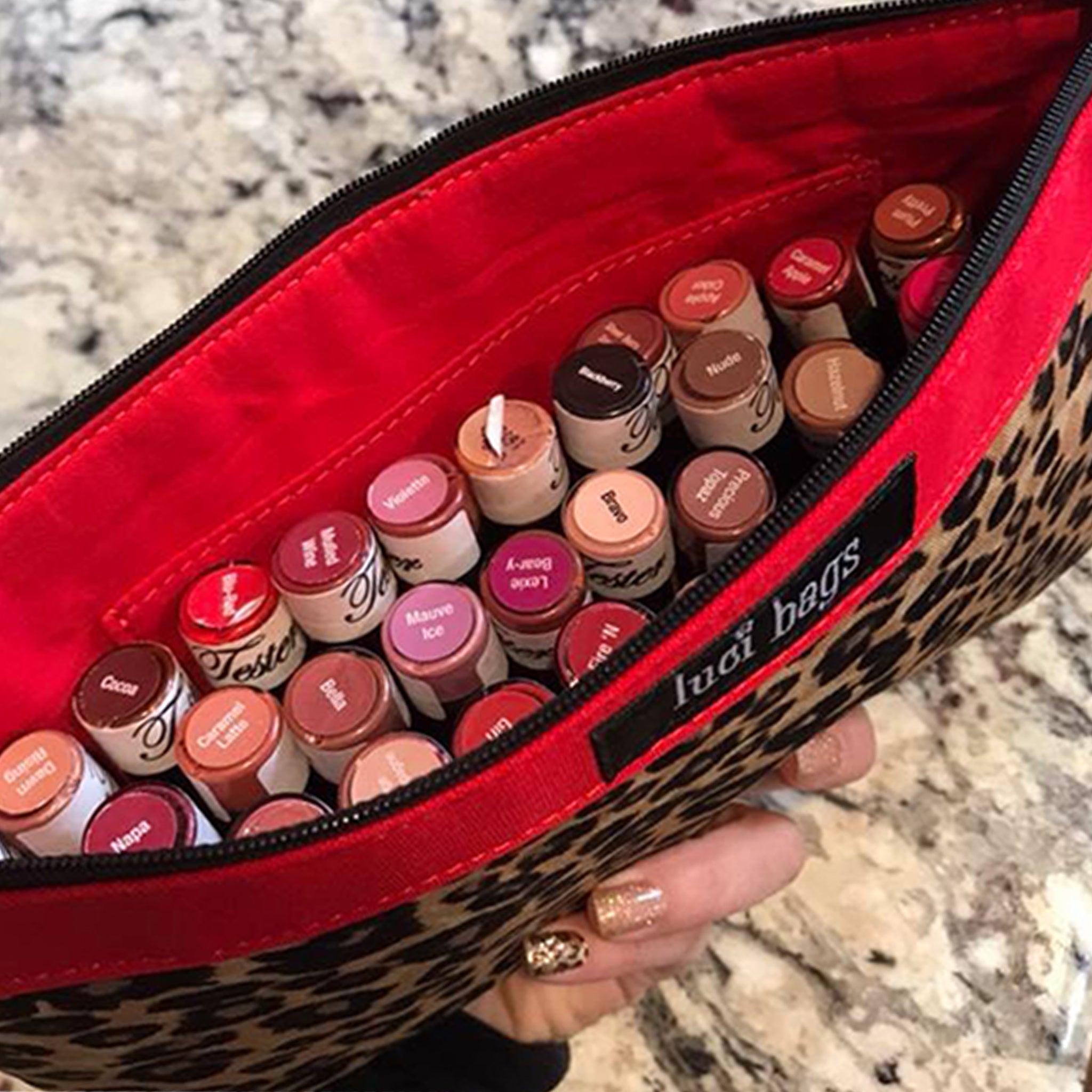 Woman holding a leopard accessory bag filled with lipstick tubes.